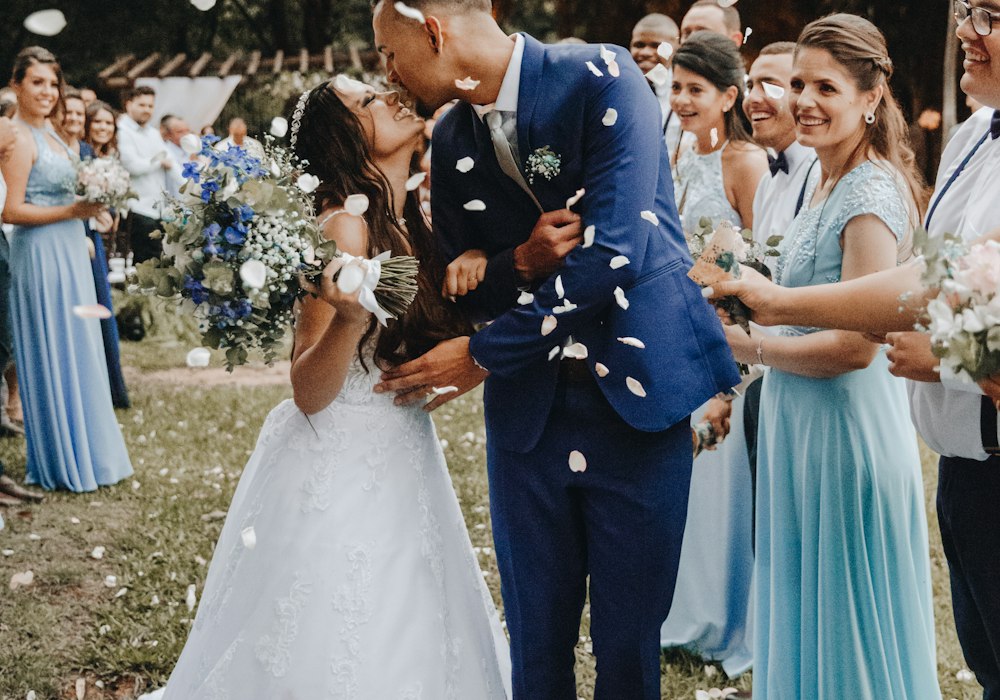 Bride and groom sharing a kiss as guests toss petals
