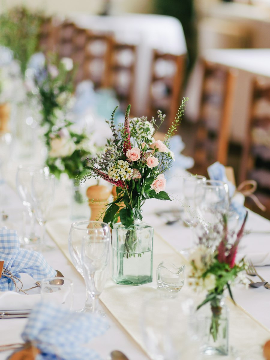 A reception table set with flowers in glass vases
